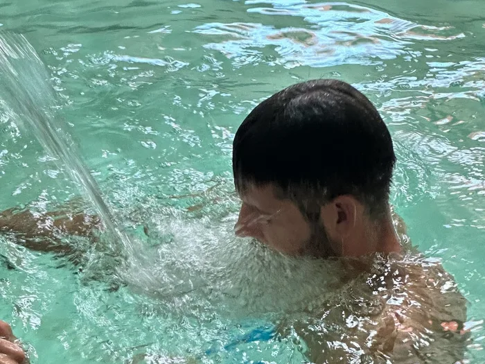 Una persona sotto il getto di acqua termale della piscina
