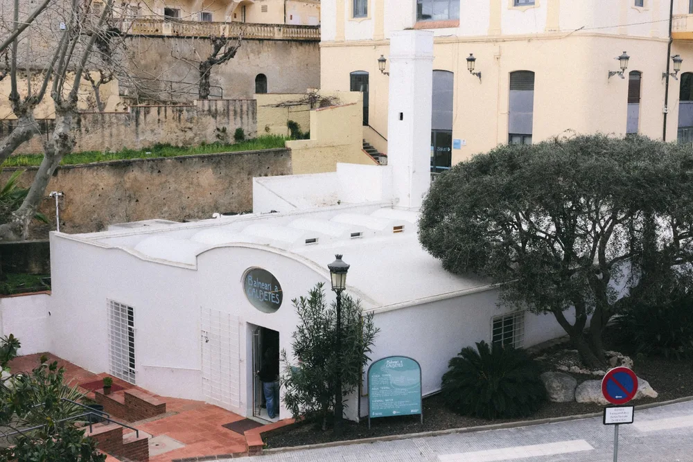 El Balneario de Caldetes visto desde la calle, con la villa y los pinos detrás