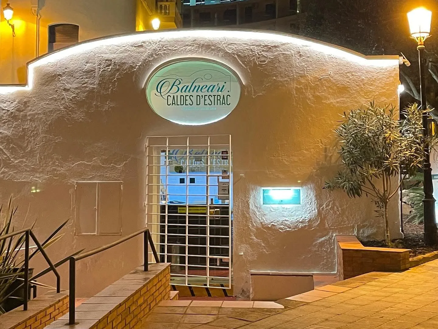 L'ingresso dello Stabilimento Termale di Caldetes illuminato di notte, con l'insegna ovale