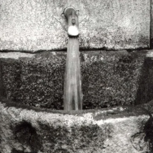 Fotografia storica in bianco e nero della fonte in pietra con l'acqua termale che sgorga
